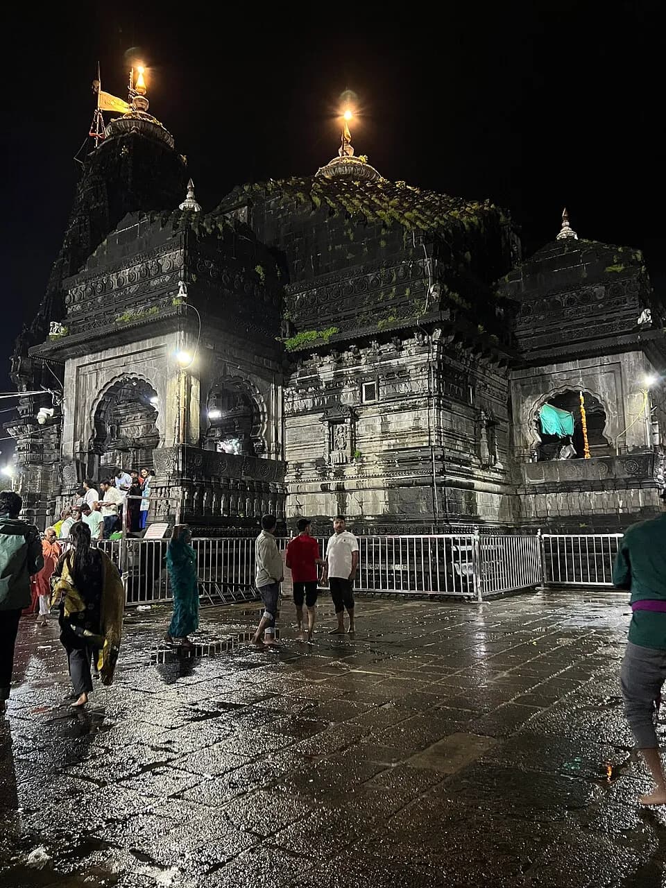 Trimbakeshwar Shiva Temple illuminated at night with pilgrims in the courtyard